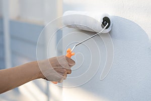 hand worker holding brush painting roller white on the wall house, diy and repair concept