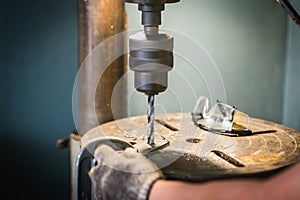 hand of worker man drills a hole in iron bracket with Pillar drilling machine
