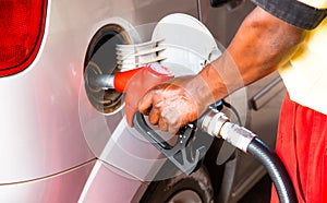 Hand of worker man refuelling a car at the petrol station. Concept photo for use of fossil fuels gasoline, diesel in combustion