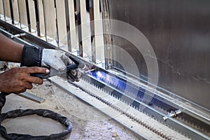 Hand of worker man Welding a stainless-steel door frame in outdo