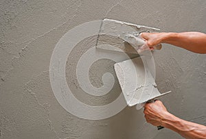 Hand of worker plastering cement wall at construction site