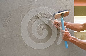 Hand of worker plastering cement wall at construction site