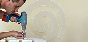 Hand of a worker screws a in a wooden board with a cordles