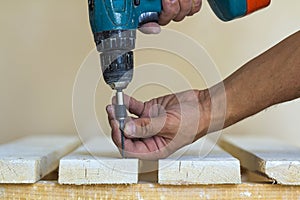 Hand of a worker screws a in a wooden board with a cordles