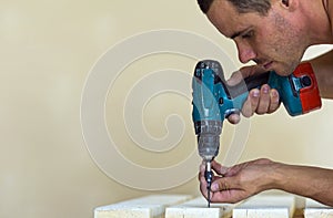 Hand of a worker screws a in a wooden board with a cordles