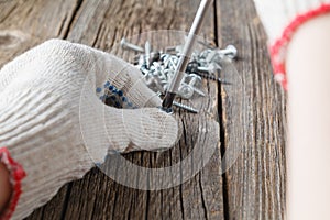 Hand of the worker screws in a wooden block with a screwdriver