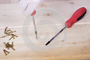 Hand of the worker screws in a wooden block with a screwdriver