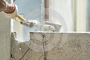 Hand of worker using hammer smashing and demolish on brick wall at construction site