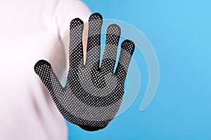 Hand in working glove, stop sign gesture. Isolated on blue background