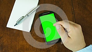 Hand working on smartphone desk green screen
