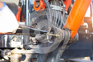 Hand of a workman greasing the grease nipple of a hydraulic cylinder the backhoe