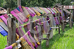 Hand woven clothes hang on wooden walkways in rice field at Sila Laeng, Pua District, Nan, Thailand