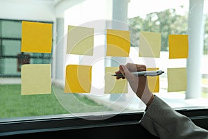 hand write on adhesive notes on glass wall. Sticky note paper re