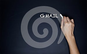 A hand writes a word Gmail on a white background.