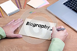 Hand writing Biography. Office desk with a laptop and stationery photo