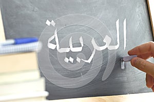 Hand writing on a blackboard in an Arabic class.