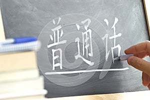 Hand writing on a blackboard in a Chinese class.