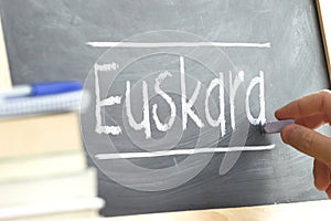 Hand writing on a blackboard in a language class with the word BASQUE wrote on