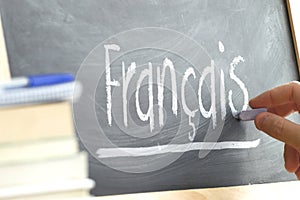 Hand writing on a blackboard in a language class with the word 