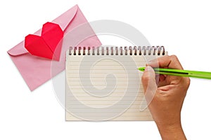 Hand writing on blank notebook with pink envelope and red heart paper origami