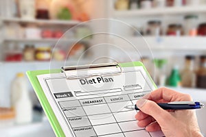 Hand Writing a Diet Plan in front of a Fridge