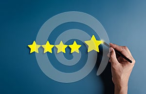 Hand writing five stars for customer feedback and evaluation in experience service and product. Excellent rating. User give rating