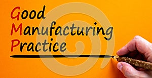 Hand writing `GMP, good manufacturing practice`, isolated on beautiful orange background. Business concept, copy space