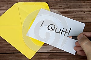 Hand writing I quit text on white notepad with yellow envelope background. Employment concept