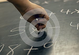 Hand writing maths equations with chalk on a blackboard. Perspective from below