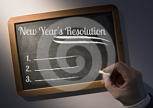 Hand writing new year resolution goals on slate board