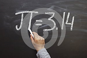 Hand writing the number Pi on a chalkboard