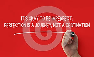 Hand writing It is okay to be imperfect affirmation on red cover background. Affirmation concept.