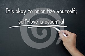 Hand writing It is okay to prioritize yourself affirmation on black board. Affirmation concept.