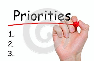 Hand writing Priorities with red marker on transparent wipe board.