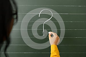 Hand writing question marks on the background of boards.