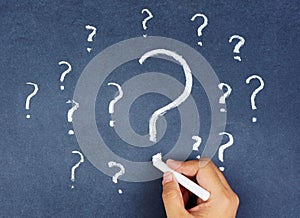 Hand writing question marks on blackboard