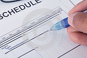 Hand writing on schedule document with pen and gantt chart