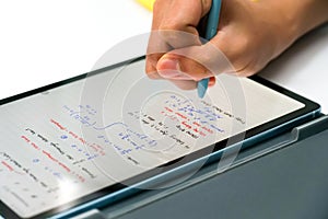 Hand writing a school lesson on tablet gadget with stylus or electric pen - concept of technology, study, and smart learning
