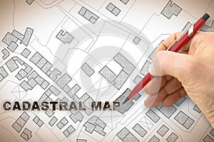 Hand writing the text -Cadastral map- on an imaginary cadastral map of territory with buildings, roads and land parcel - concept