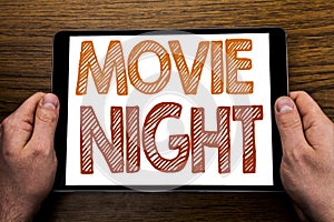 Hand writing text caption Movie Night. Business concept for Wathing Movies Written on tablet laptop, wooden background with busin