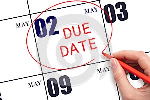 Hand writing text DUE DATE on calendar date May 2 and circling it. Payment due date