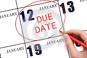 Hand writing text DUE DATE on calendar date January 12 and circling it. Payment due date