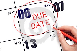 Hand writing text DUE DATE on calendar date May 6 and circling it. Payment due date