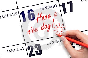 The hand writing the text Have a nice day and drawing the sun on the calendar date January 16