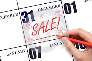 Hand writing text SALE and drawing gift boxes on calendar date December 31. Shopping Reminder
