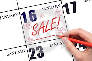 Hand writing text SALE and drawing gift boxes on calendar date January 16. Shopping Reminder