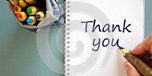 Hand writing `thank you`, isolated on blue background. Bag with pencils