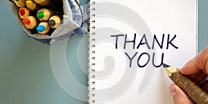 Hand writing `thank you`,  on blue background. Bag with pencils. Concept