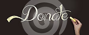 Hand writing the word Donate with chalk on blackboard. Donation help volunteers support concept