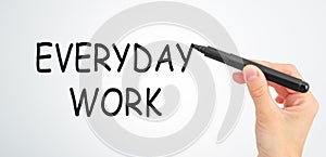 A hand is writing the word Everyday Work on a white background.
